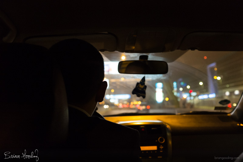 A driver silhouetted at night, with city lights through the windshield.
